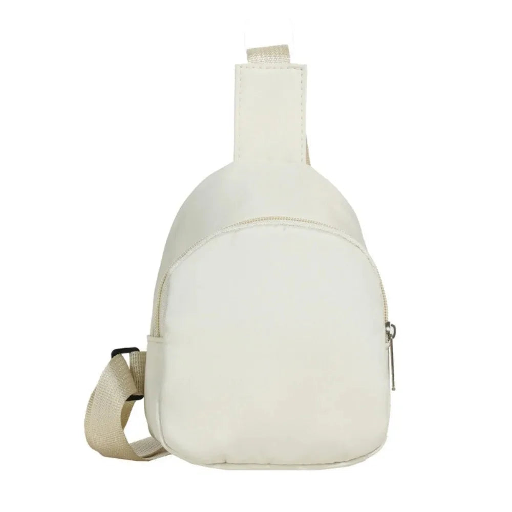 A cream-colored nylon crossbody bag for kids with a flap closure.