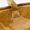 Primer plano de un bolso tote minimalista de PVC marrón mostrando costuras y textura de cuero.