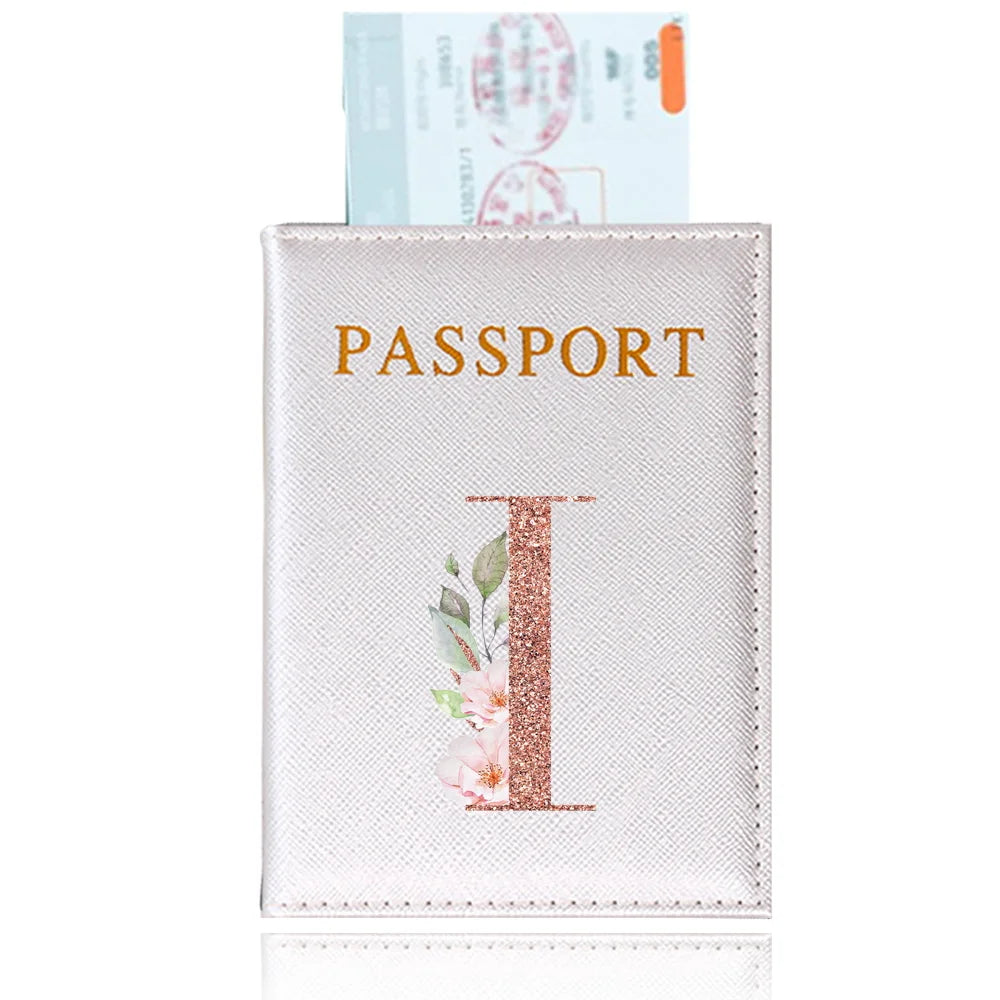 A light pink leather passport holder featuring a gold embossed letter I and a passport visible in the background.