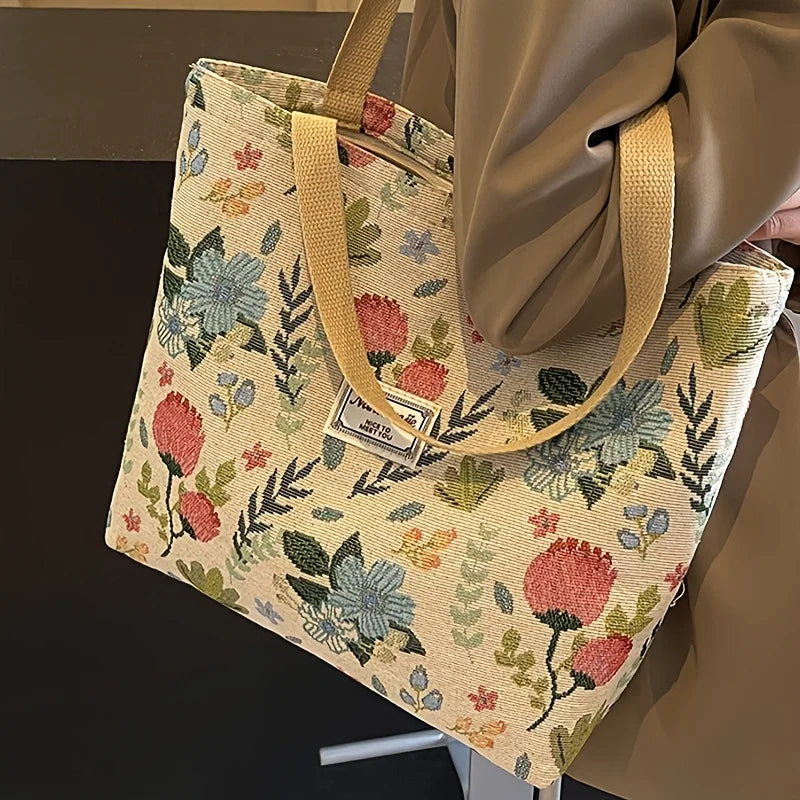 A beige bohemian corduroy tote bag with floral embroidery is shown hanging on a hanger.