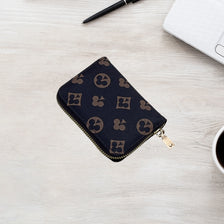 Portefeuille à fermeture éclair à motif foncé sur une surface en bois clair, à côté d'un stylo et d'un ordinateur portable.