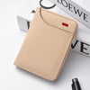A light beige slim bi-fold wallet for men resting on a white surface next to some books.