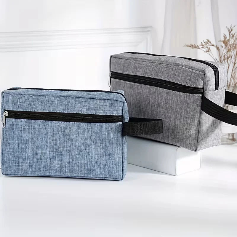A gray and blue fabric toiletry bag set with black trim resting on a white surface.