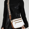A black leather jacket is shown holding a white and brown retro square crossbody bag with an adjustable strap.