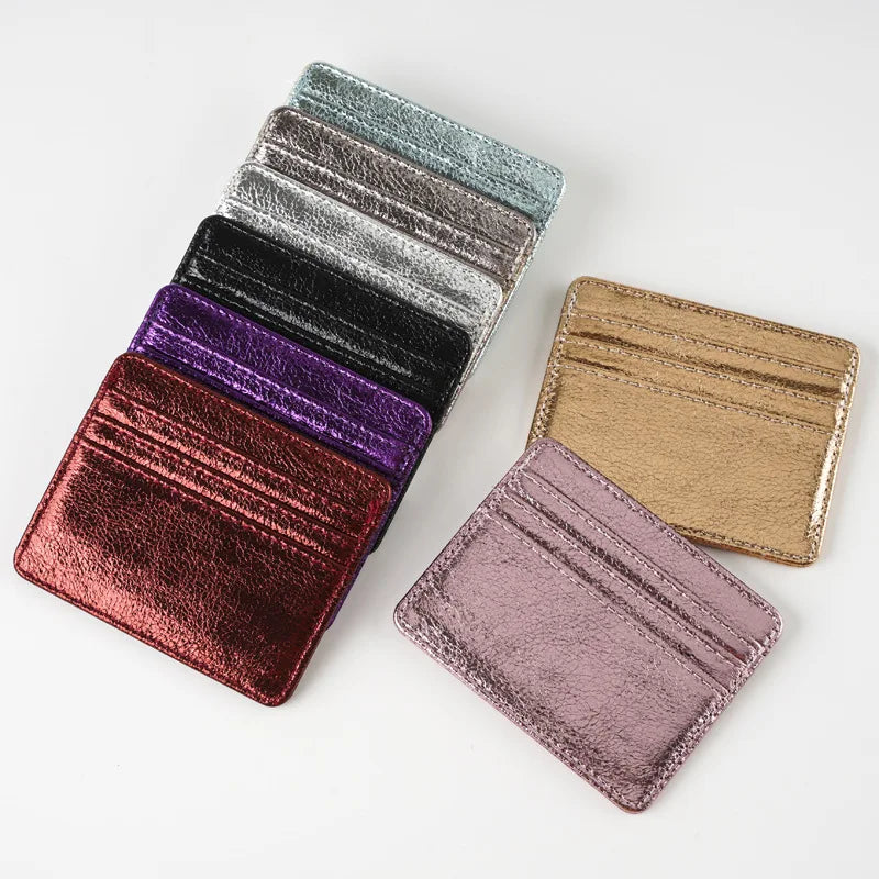 A stack of slim leather mini wallet card holders in various shades including black, purple, and gold.