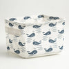 A white storage basket with a blue whale pattern, made of foldable cotton linen, shown from above.