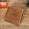 A brown leather wallet with a compass design is placed on a wooden surface next to some books.