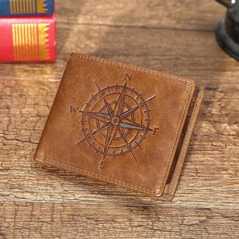 A brown leather wallet with a compass design is placed on a wooden surface next to some books.