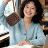 A young woman smiling while holding a brown mini coin purse and card holder wallet next to an open notebook.