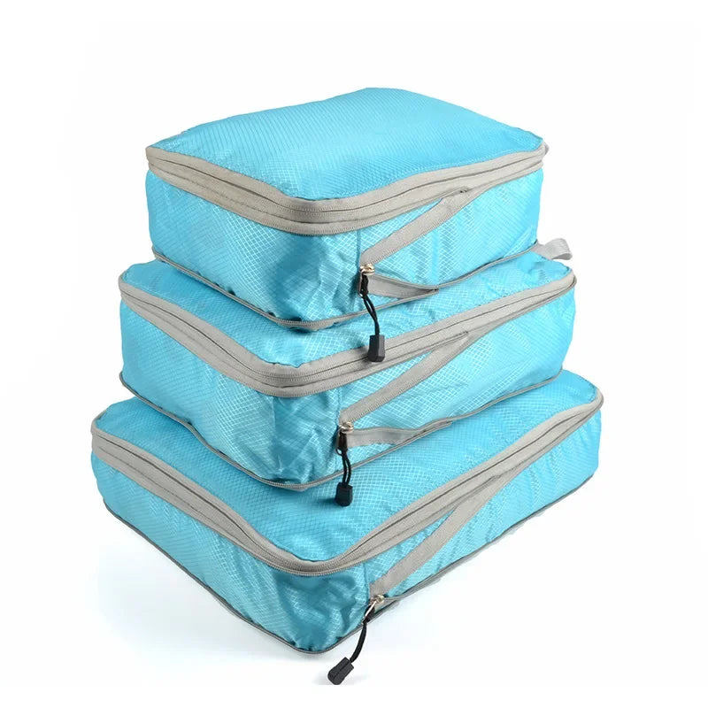 A set of three light blue reusable compression packing cubes with gray zippers.