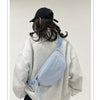 A woman wearing a light gray sweatshirt holds a light blue corduroy waist pack against her back.