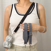A woman wearing a white tank top holds an adjustable wide shoulder strap for bags and cameras.