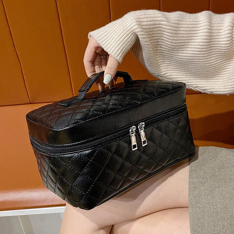 A black quilted makeup storage pouch is held by a hand against an orange leather background.