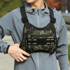 A young man wearing a light blue jacket is holding a black tactical chest rig vest bag for outdoor gear.