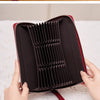 A close-up of a maroon leather wallet with a zipper closure being held by a hand.