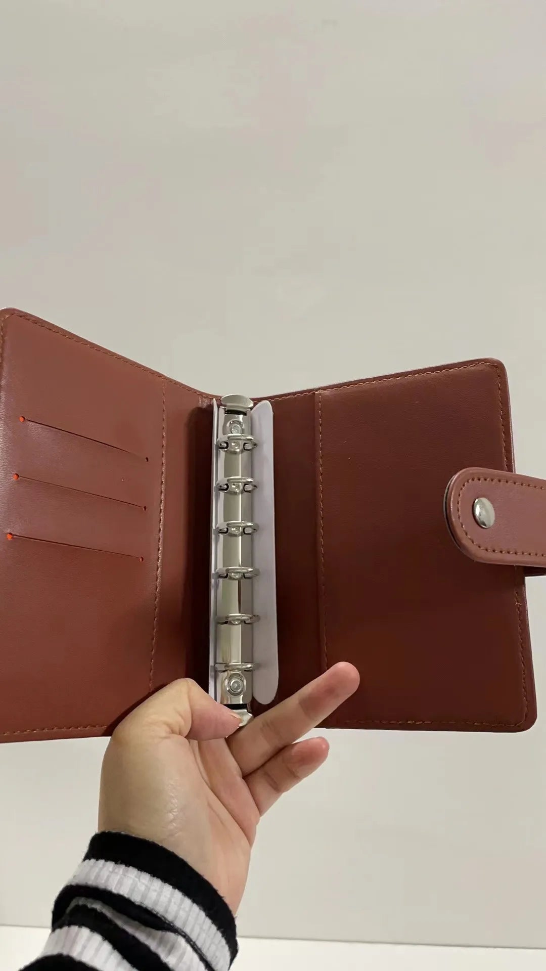 A close-up of a brown leather A7 crocodile ring binder notebook being held open.