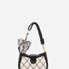 A black and white quilted bag with a bow detail and a black leather strap.