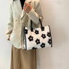 A woman is holding a white blazer and a black faux fur leopard print designer shoulder tote bag.
