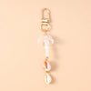 Gold-toned starfish keychain featuring a clear glass charm and a pink seashell pendant with pearl accents