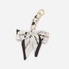 A white and black patterned adjustable bag strap with a gold-toned metal clasp.