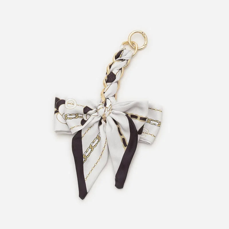A white and black patterned adjustable bag strap with a gold-toned metal clasp.