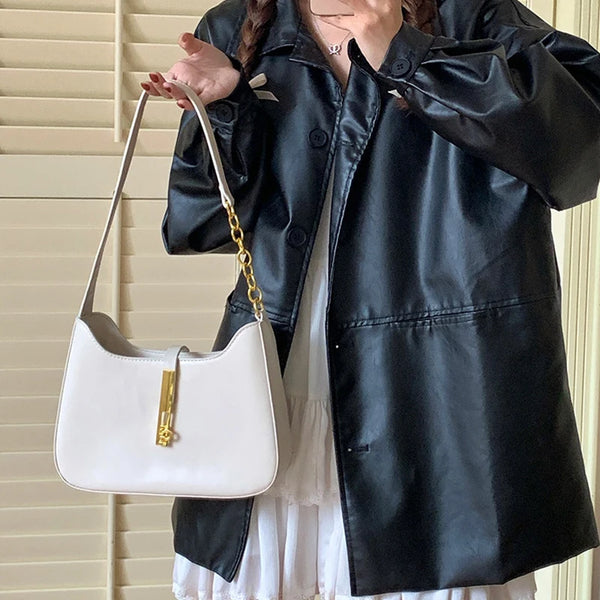 A woman holds a white leather hobo shoulder bag with a gold chain strap against a background of light blinds and a black leat