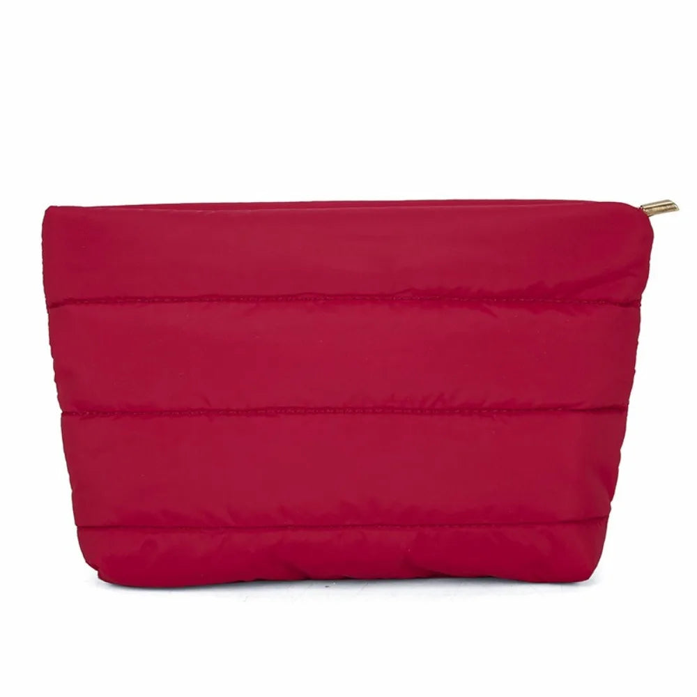 A vibrant red quilted cosmetic travel bag with a gold zipper.
