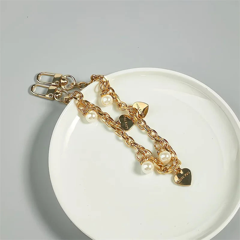 Goldkette mit Perlenakzenten und einem Herzanhänger auf weißem Teller.