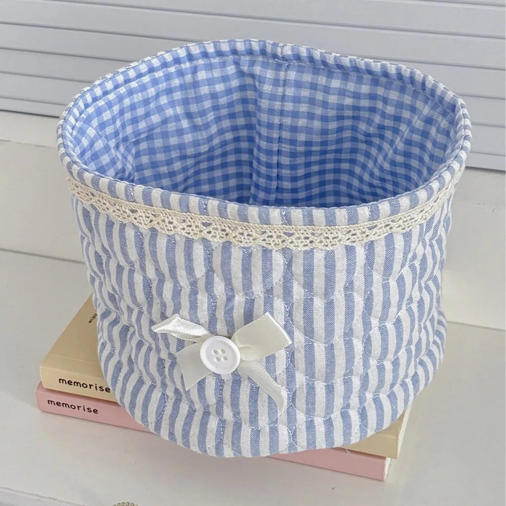 Cesta de guardado con corazón de tela de colcha azul claro y blanco a rayas sobre una superficie blanca.
