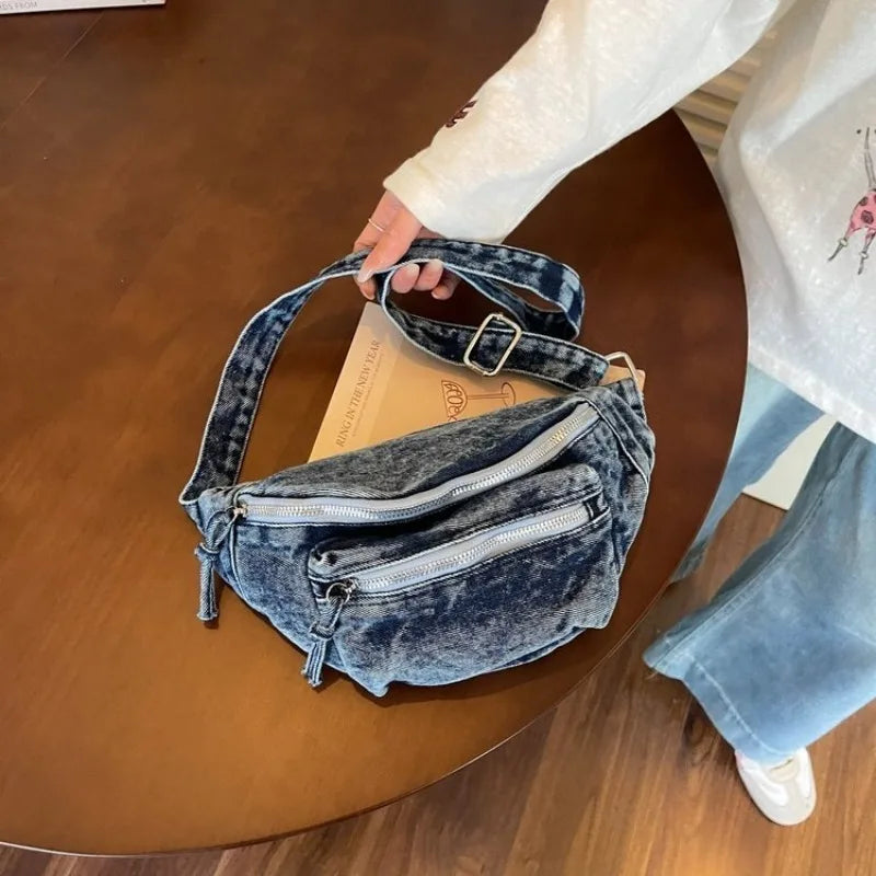 Un sac bandoulière en jean vintage délavé bleu foncé posé sur une table en bois.