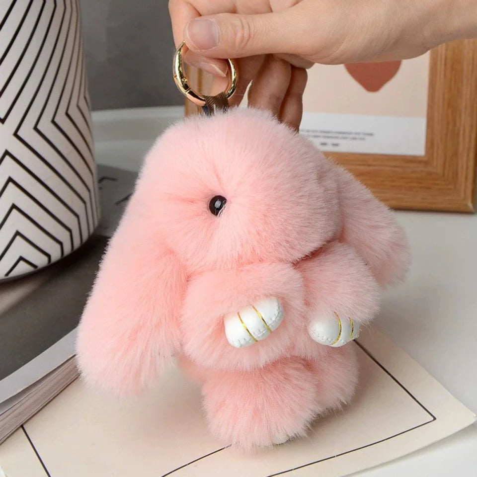 A fluffy pink rabbit plush toy with white accents is being held by a hand, displayed on a light background.