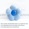 A light blue, flower-shaped phone grip ring stand with small black dots on the surface.