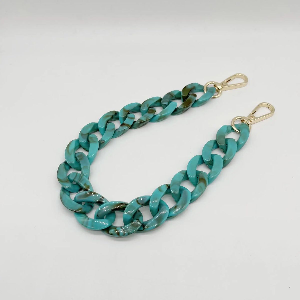 A close-up of a turquoise blue acrylic chain bracelet with gold-colored clasps.