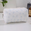 Bolsa de maquillaje acolchada blanca con detalles de lazos azul claro.