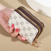 A hand holds a beige and white patterned zippered card holder wallet.