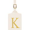 Étiquette de bagage rectangulaire en cuir beige avec un K brodé en or et un clip métallique argenté.