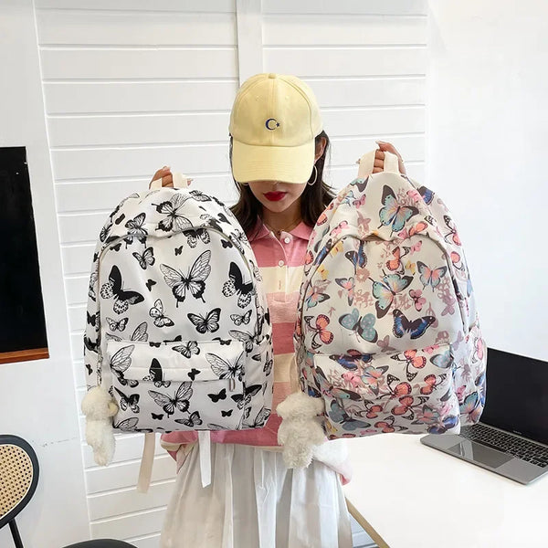 Una mujer con gorra amarilla sostiene una mochila rosa con estampado de mariposa floral para mujeres.