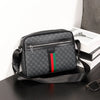 A black men's letter print crossbody sling bag with a silver zipper resting on a dark surface.