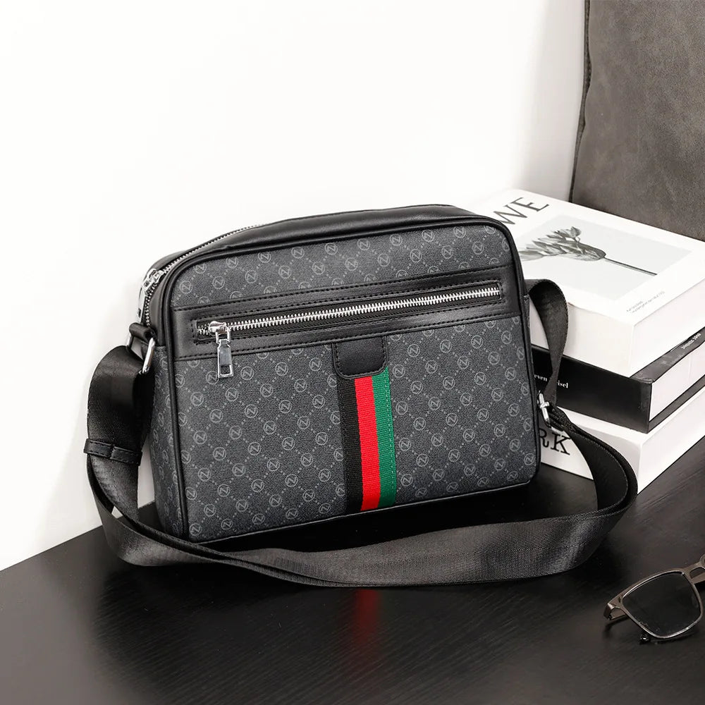 A black men's letter print crossbody sling bag with a silver zipper resting on a dark surface.
