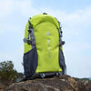A bright lime green hiking backpack resting on a large rock under a light blue sky.