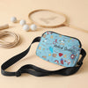 A blue medical doodle print crossbody waist bag resting on a light beige surface with a tennis racket and balls nearby.