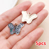 A set of five colorful butterfly enamel charms displayed on a person's hand.