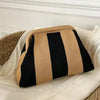 Clutch de tejido hecho a mano con rayas verticales beige y negro sobre una superficie de tela blanca.