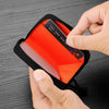 A hand is opening a black RFID zipper wallet to reveal an orange interior and a credit card.