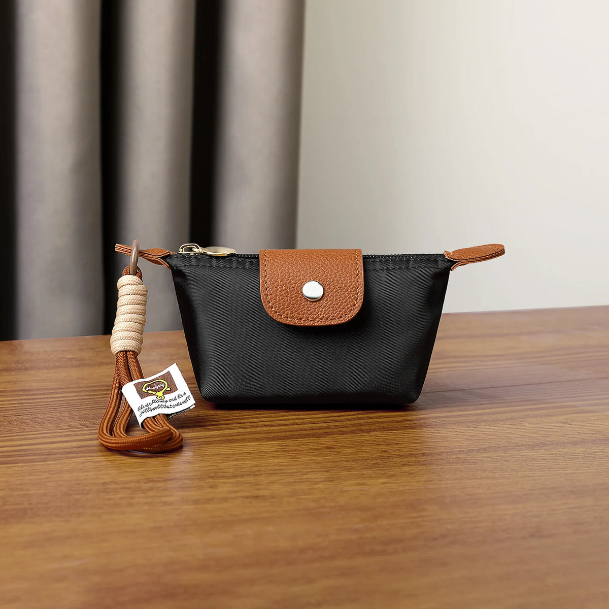 Schwarze Leder-Geldbörse mit brauem Klapp und geflochtenem Armband auf Holzoberfläche.