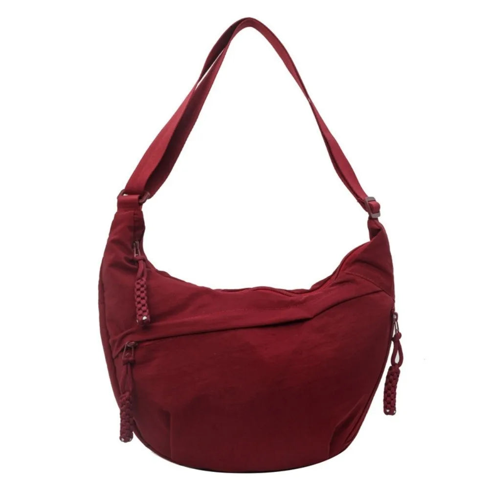 A deep burgundy canvas crossbody shoulder bag with a long strap.