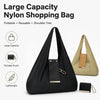 Sac de shopping noir en nylon pliable avec une pochette en cuir et un sac à main beige, à côté d'un petit portefeuille noir