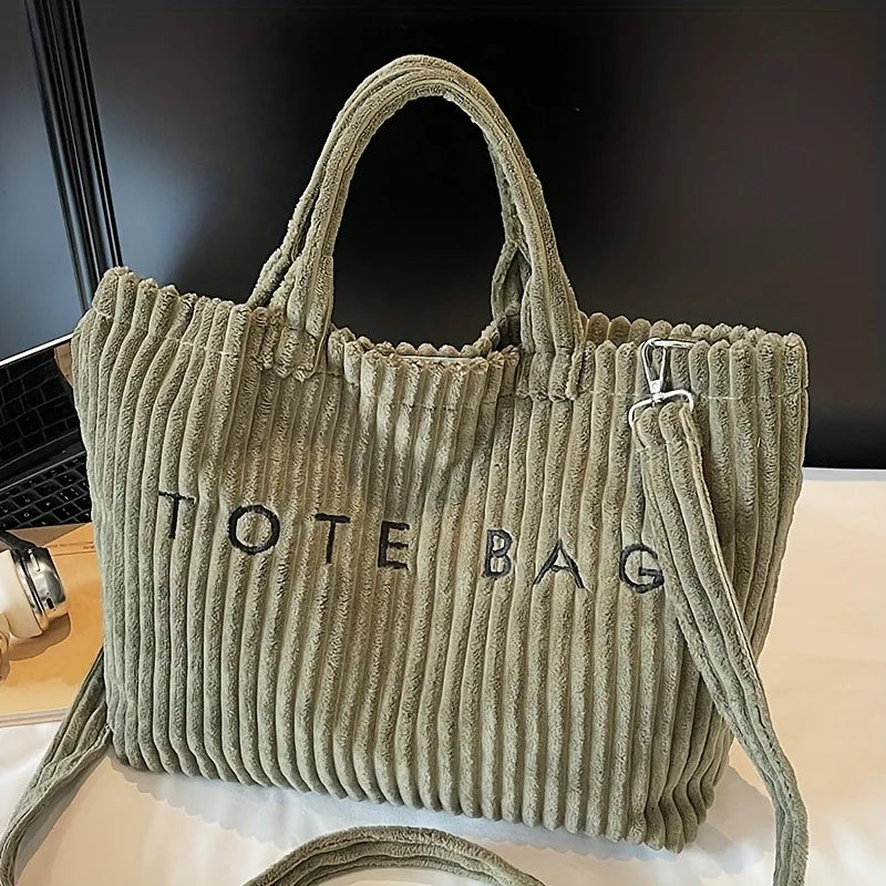 Sac en toile vert olive texturé à rayures verticales et lettrage noir sur fond blanc.