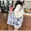 A woman holds a transparent shoulder tote bag featuring various character images and a cream-colored sweater.
