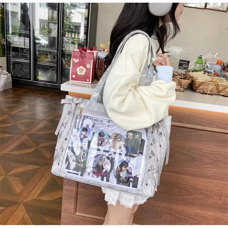 A woman holds a transparent shoulder tote bag featuring various character images and a cream-colored sweater.